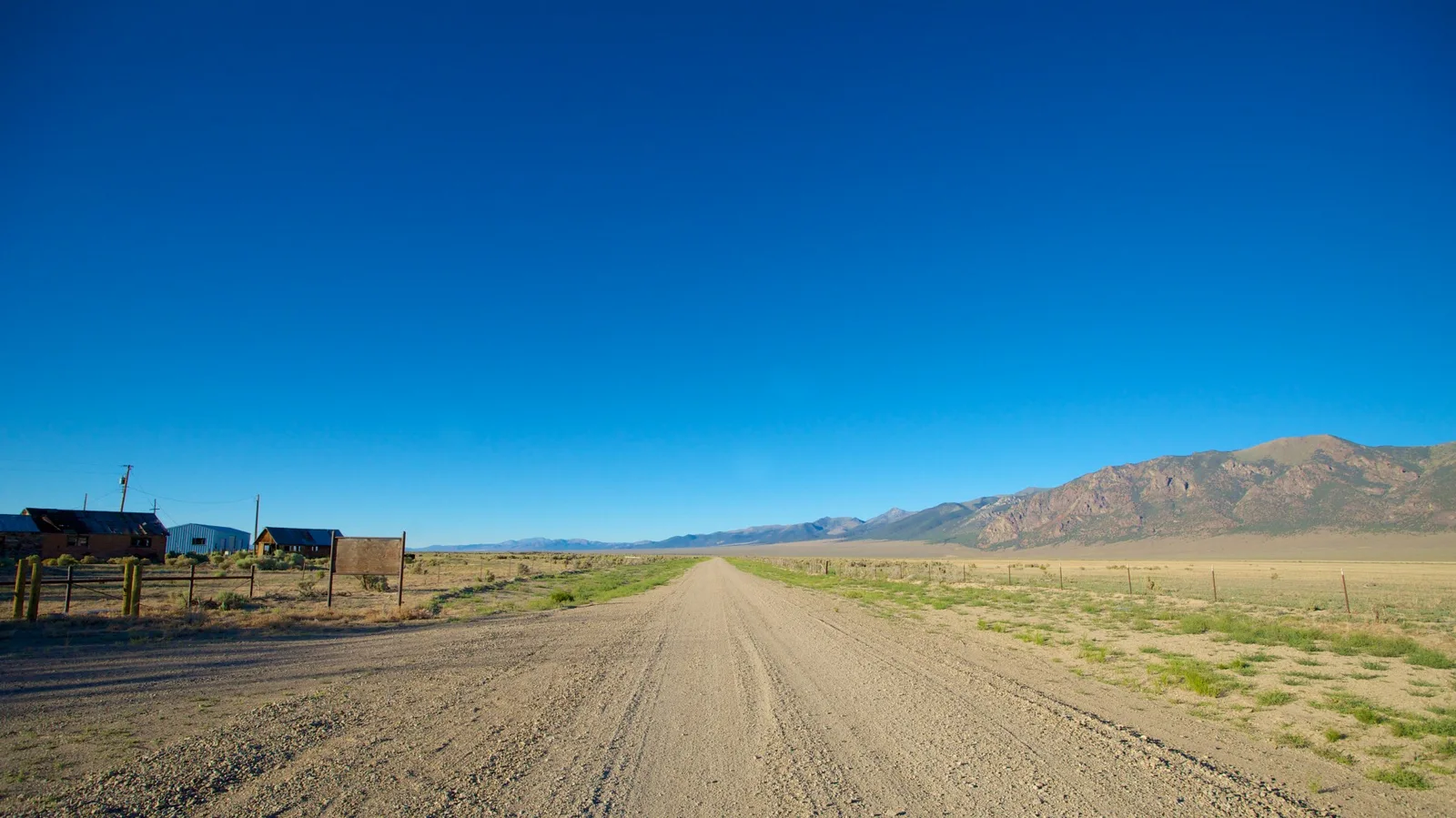 A gravel track crossing open high-desert terrain toward distant mountains